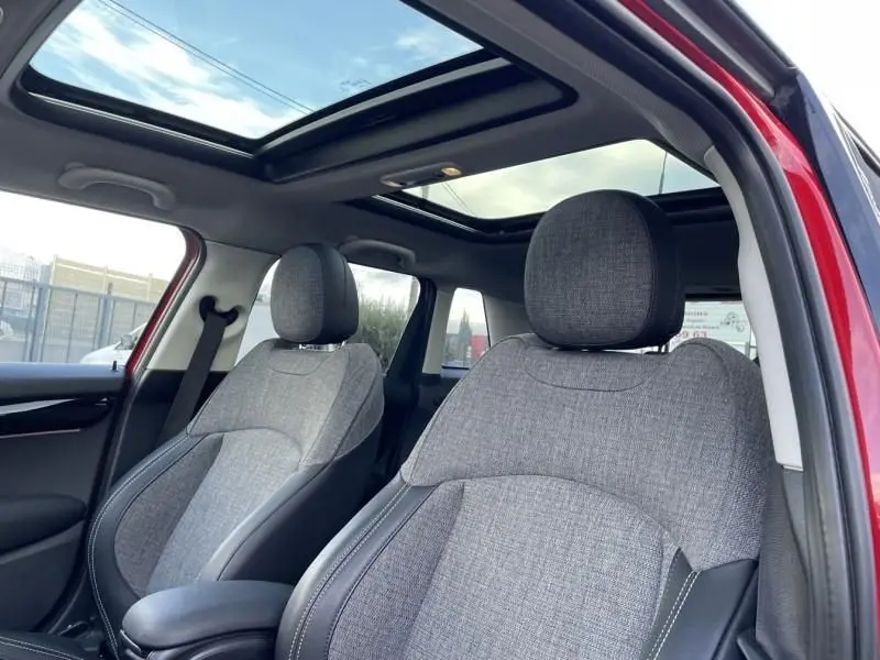 Intérieur de la MINI 5P Cooper D rouge 2021, vue côté avant droit sur sièges gris et toit panoramique ouvert.