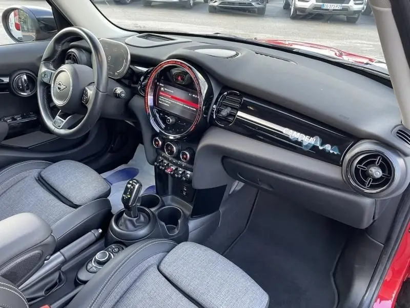 Vue intérieure côté conducteur de la MINI 5P Cooper D rouge, avec tableau de bord et écran central lumineux Edition Camden.