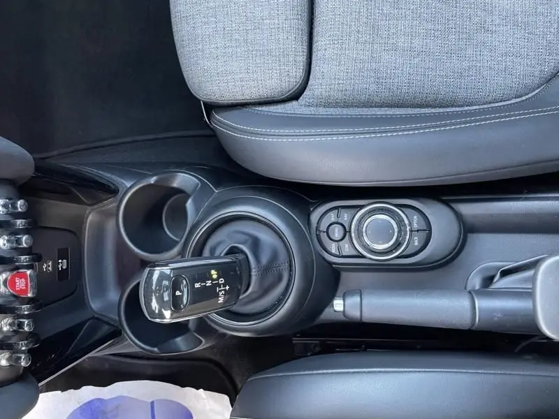 Vue rapprochée de la console centrale de la MINI 5P Cooper D rouge 2021, avec levier de boîte auto et commandes circulaires.