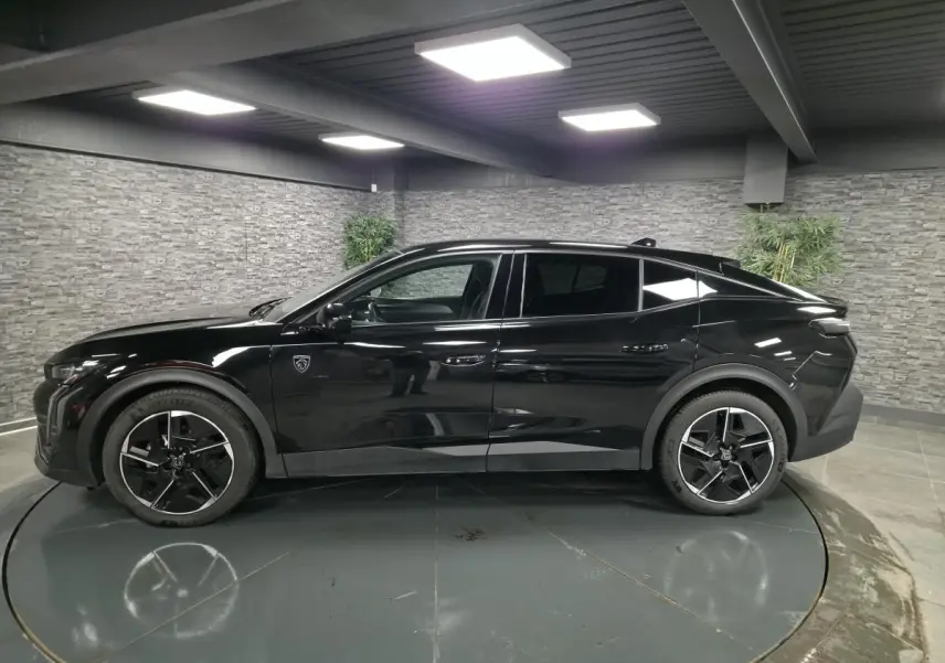 Peugeot 408 hybride noire vue de profil côté gauche, avec jantes alliage 19 pouces et toit plongeant.