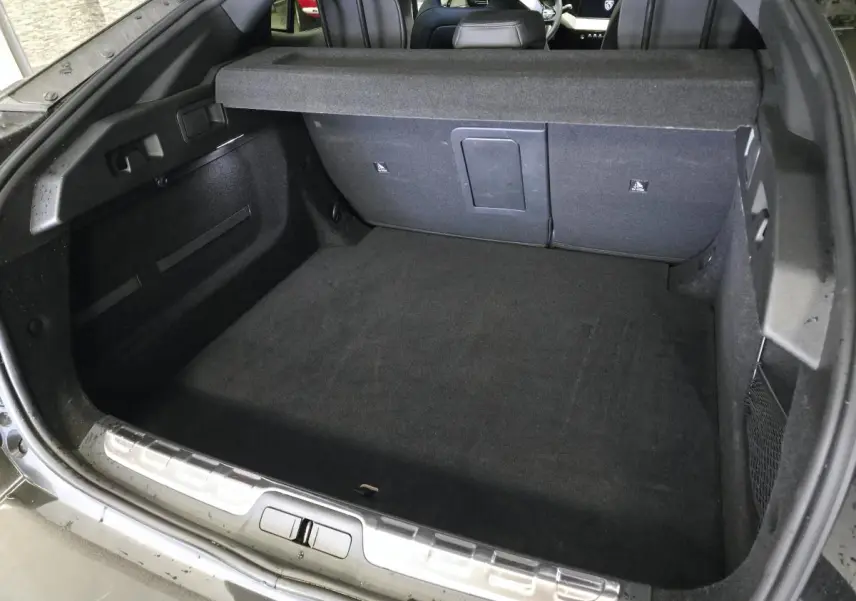 Coffre ouvert vu de l'arrière d'une Peugeot 408 noire, montrant un espace de chargement propre et spacieux.