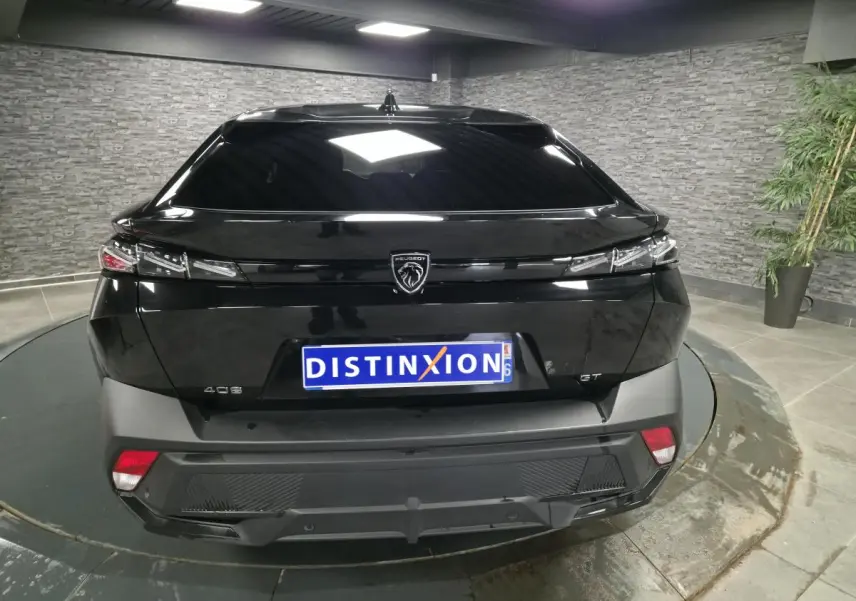 Vue arrière d'une Peugeot 408 noire avec feux arrière fins et logo lion central sur fond noir brillant.