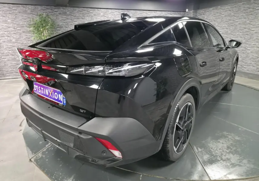 Vue 3/4 arrière droite d'une Peugeot 408 GT noire avec jantes alliage 19 pouces et feux arrière LED griffés.