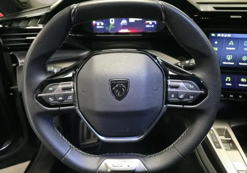 Volant cuir perforé noir de la Peugeot 408 GT 2024 avec commandes intégrées et instrumentation numérique en arrière-plan.