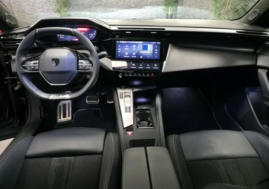 Vue intérieure avant du Peugeot 408 GT 2024 noir, avec volant cuir, écran tactile 10 pouces et console centrale moderne.