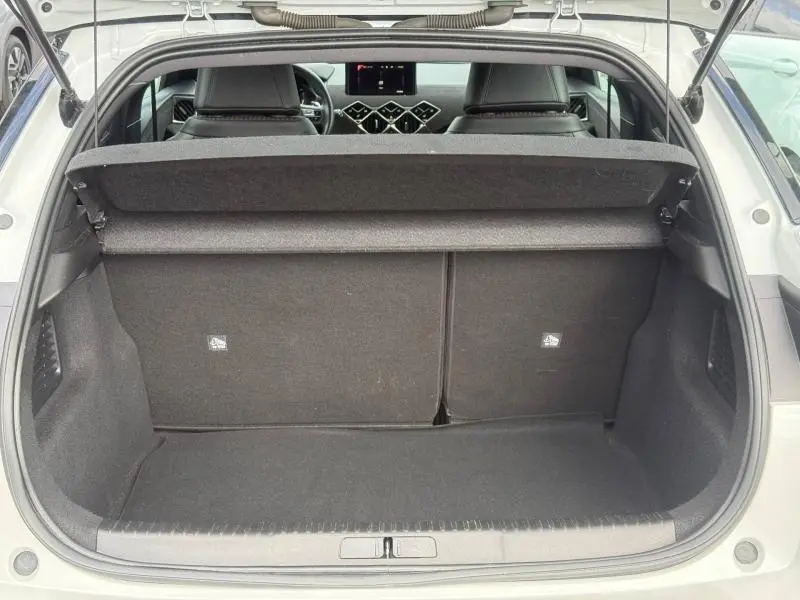 Vue du coffre ouvert d'une DS3 Crossback blanc perle nacré, intérieur noir avec tablette cache-bagages déployée.