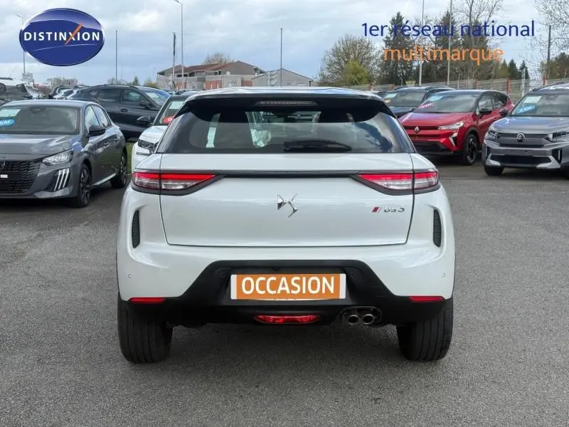 Vue arrière d'une DS3 Crossback blanc perle nacré avec toit noir et double sortie d'échappement à droite.