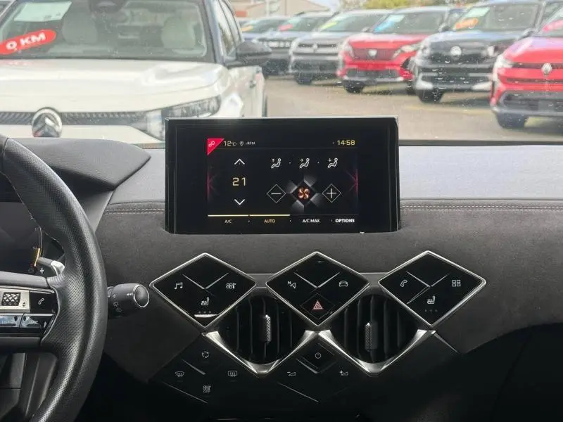 Vue intérieure centrée sur la console centrale et l'écran tactile du DS3 Crossback blanc perle avec toit noir, volant partiel à gauche.