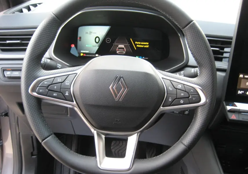 Vue rapprochée du volant noir perforé et du tableau de bord numérique du Renault Symbioz gris Rafale, version hybride 2025.