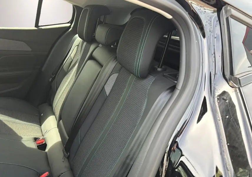 Vue intérieure côté arrière droit d’une Peugeot 408 noire, montrant la banquette arrière en tissu avec surpiqûres contrastantes.