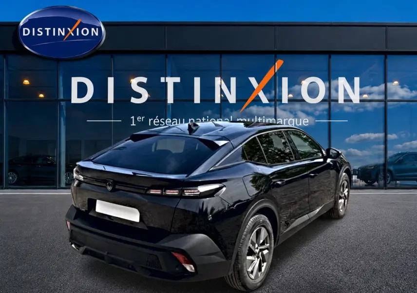 Vue 3/4 arrière droite d'une Peugeot 408 Hybrid 136 allure e-dcs6 noire, avec vitres surteintées et jantes alu devant un showroom Distinxion.