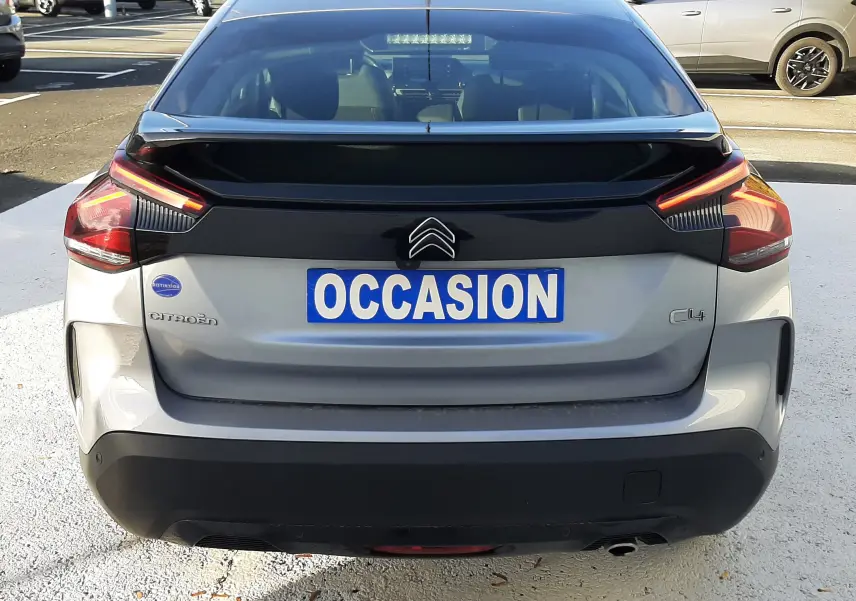 Vue arrière d'une Citroën C4 gris clair 2023 avec feux LED et logo distinctif sur un parking.