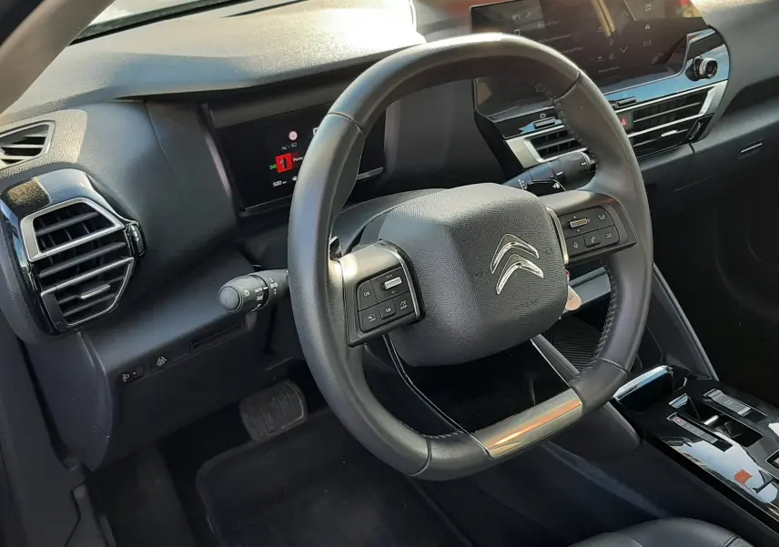 Vue intérieure côté conducteur de la Citroën C4 2023 gris, volant multifonction et tableau de bord digital moderne.
