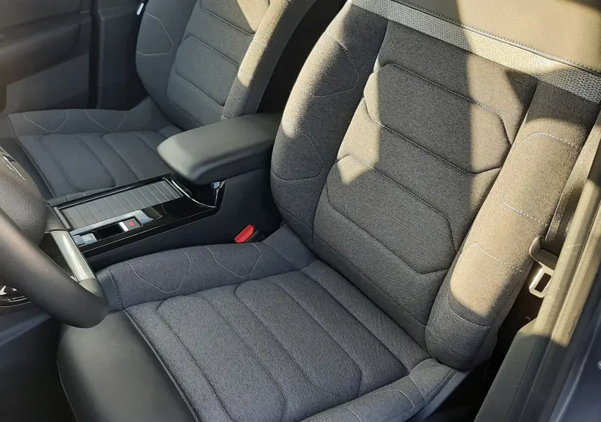 Vue rapprochée des sièges avant gris en tissu et cuir d’une Citroën C4 2023, mettant en valeur l’accoudoir central.