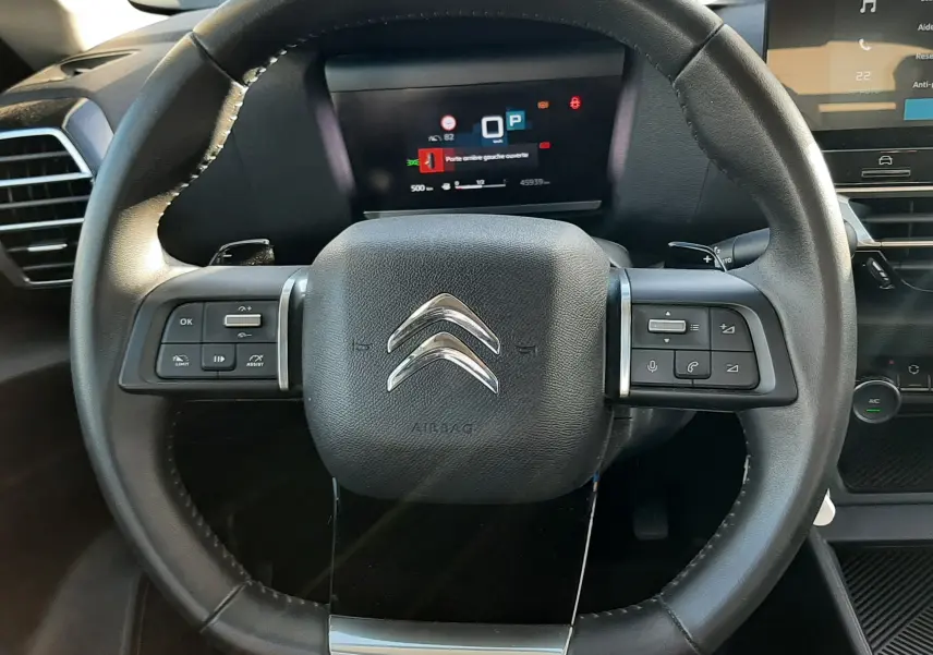 Vue rapprochée du volant cuir noir du Citroën C4 2023 avec commandes intégrées et tableau de bord numérique.