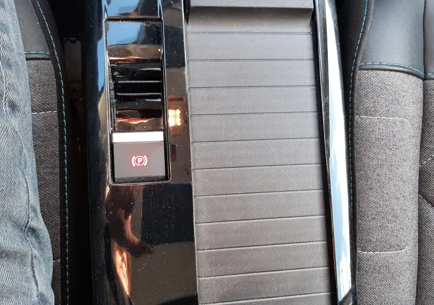 Vue rapprochée de la console centrale noire avec frein à main électronique dans l'habitacle gris du Citroën C4 2023.