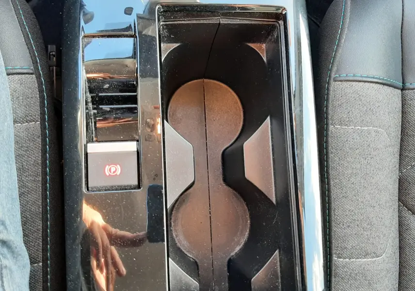 Vue plongeante sur la console centrale noire brillante avec porte-gobelets et frein à main électrique d'une Citroën C4 gris 2023.