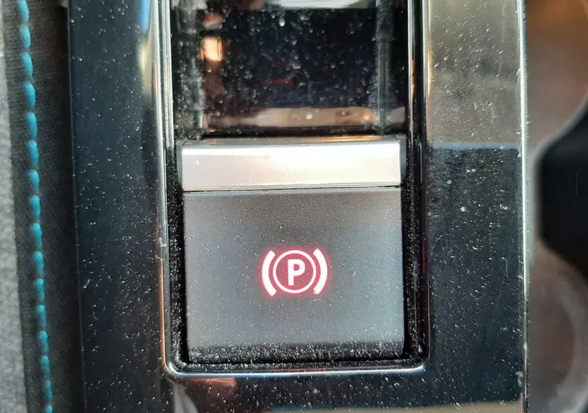 Gros plan sur le bouton de frein à main électronique illuminé en rouge dans l'habitacle gris d'une Citroën C4 2023.
