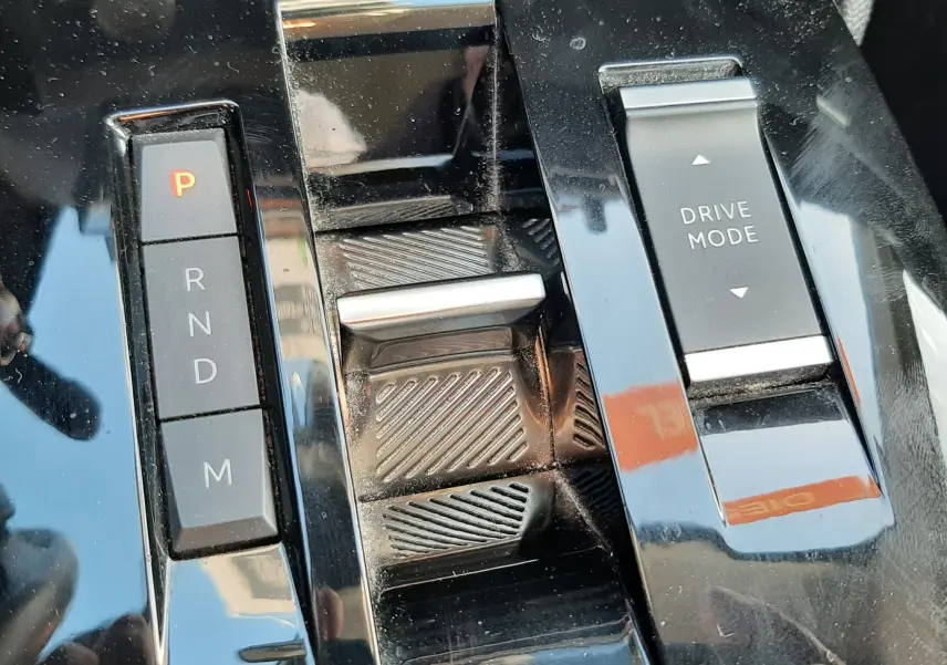 Gros plan sur la console centrale noire brillante de la Citroën C4 2023, avec levier de vitesses automatique et bouton Drive Mode.