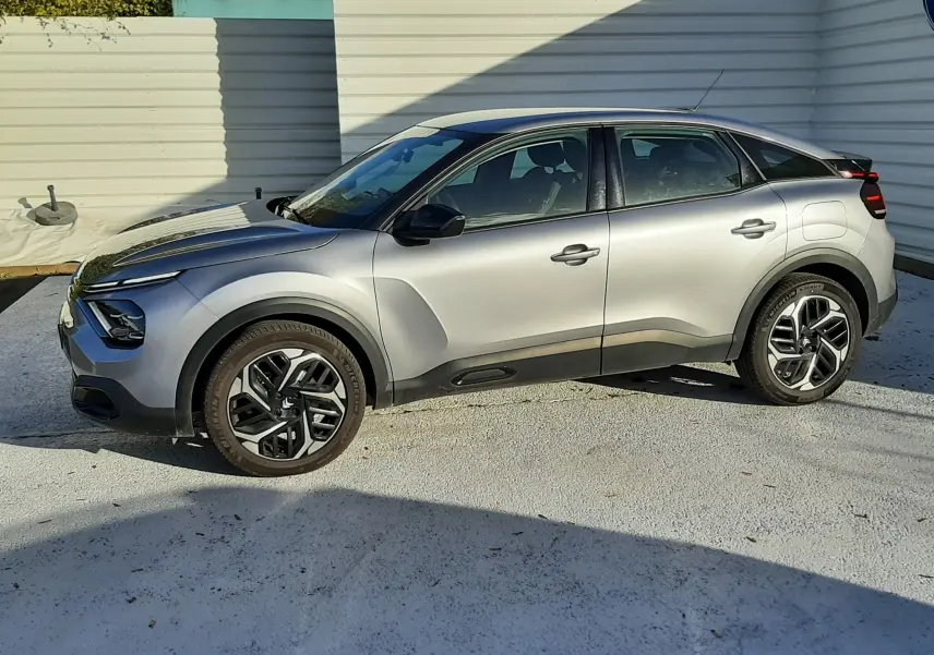 Citroën C4 gris vue de profil côté gauche, avec jantes bi-ton et lignes sculptées sur les ailes.