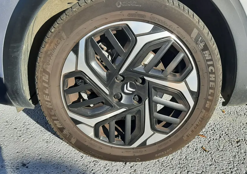 Gros plan sur la roue avant droite grise d'une Citroën C4 2023 avec jante alliage bicolore et pneu Michelin.