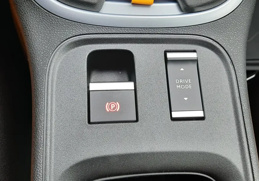 Gros plan sur la console centrale du Jeep Avenger 2025, boutons frein électrique et mode de conduite visibles.