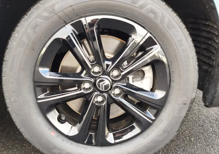 Gros plan sur la jante noire brillante avec logo Citroën au centre, montée sur un pneu Nexen d’un Berlingo bleu Kiarma.