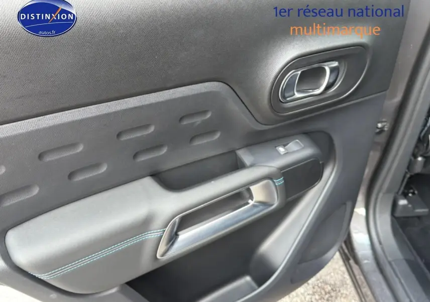 Gros plan sur la porte intérieure côté droit du Citroën C5 Aircross gris platinium avec surpiqûres bleues et poignée argentée.