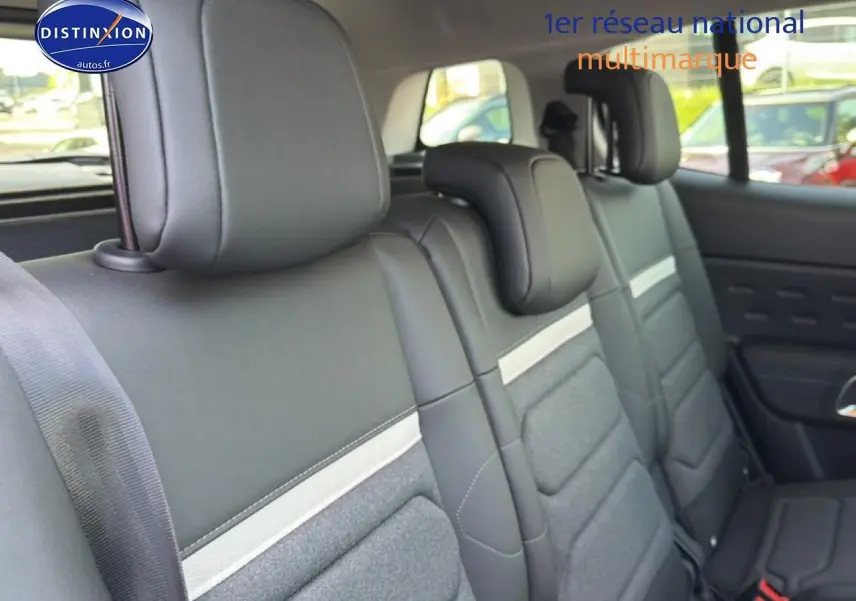 Vue latérale intérieure sur la deuxième rangée de sièges noirs et gris du Citroën C5 Aircross 2025 hybride.
