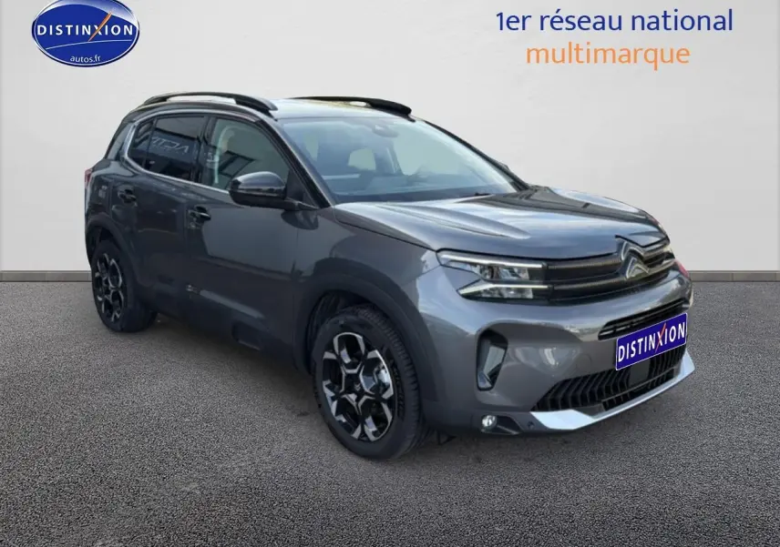 Citroën C5 Aircross gris platinium en 3/4 avant droit, avec barres de toit et jantes alu distinctives.