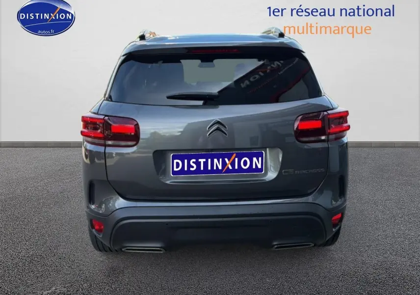 Vue arrière d'un Citroën C5 Aircross gris platinium avec feux LED et barres de toit visibles.