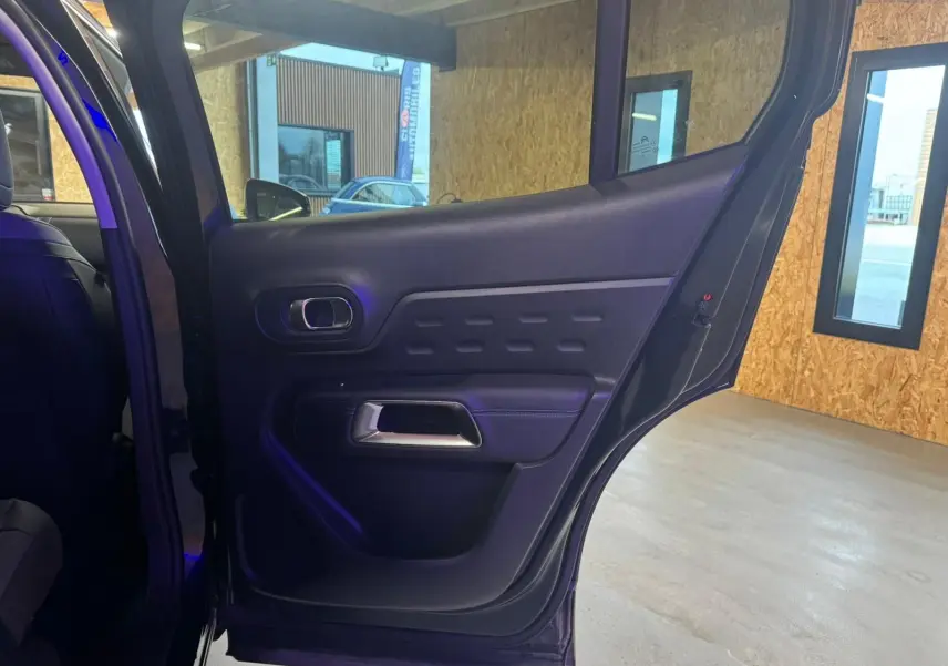 Gros plan sur la porte arrière gauche intérieure du Citroën C5 Aircross bleu, avec poignée argentée et panneau noir texturé.