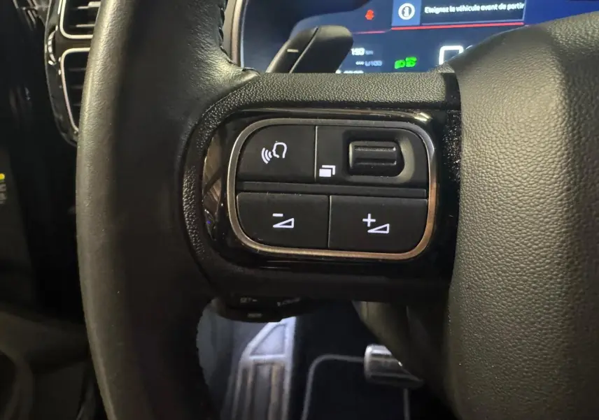 Vue rapprochée du volant en cuir noir du Citroën C5 Aircross avec commandes intégrées et tableau de bord numérique.
