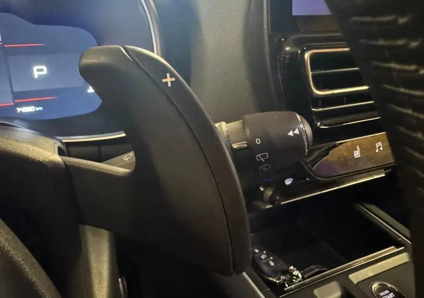 Gros plan sur la palette de changement de vitesses droite noire dans l’habitacle du Citroën C5 Aircross bleu, avec tableau de bord numérique en arrière-plan.