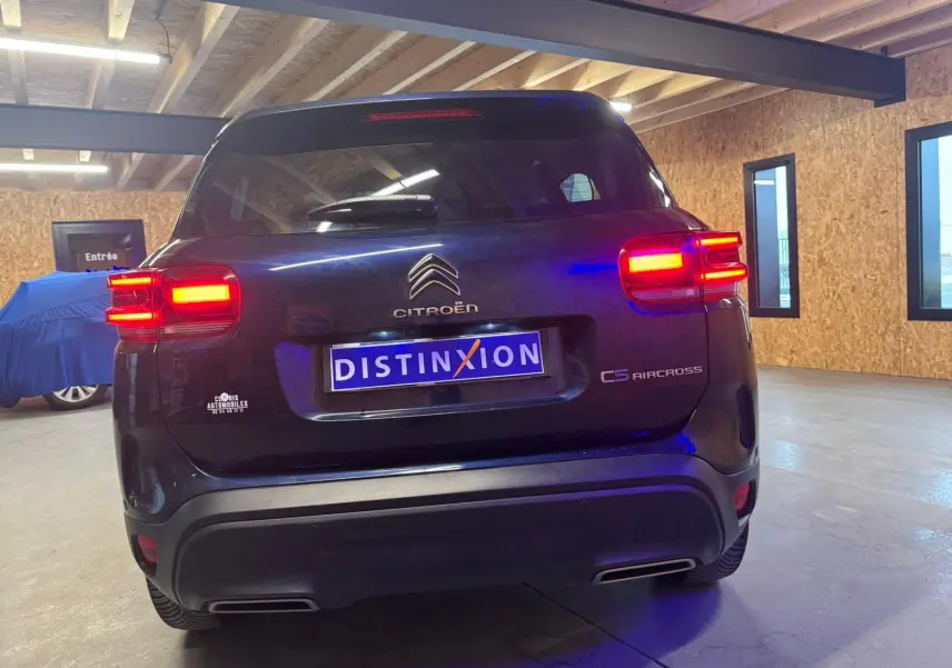 Vue 3/4 arrière droite du Citroën C5 Aircross bleu avec feux arrière LED allumés en intérieur.