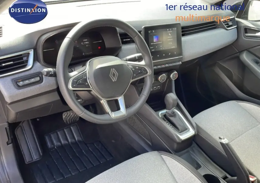 Vue intérieure côté conducteur de la Renault Clio 2025, volant cuir, tableau de bord gris et console centrale avec écran tactile.