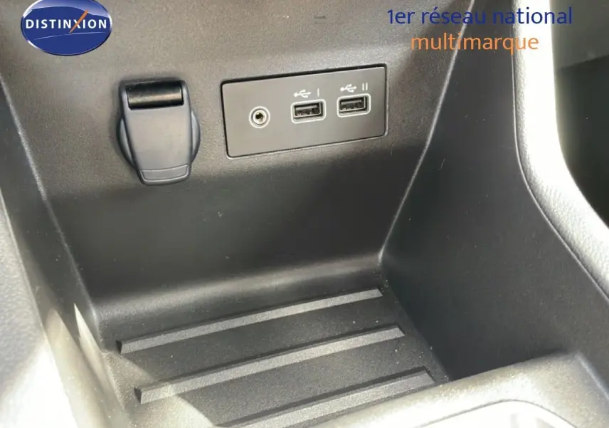 Prise USB et prise auxiliaire dans le rangement central d’une Renault Clio gris schiste métal, vue intérieure rapprochée.