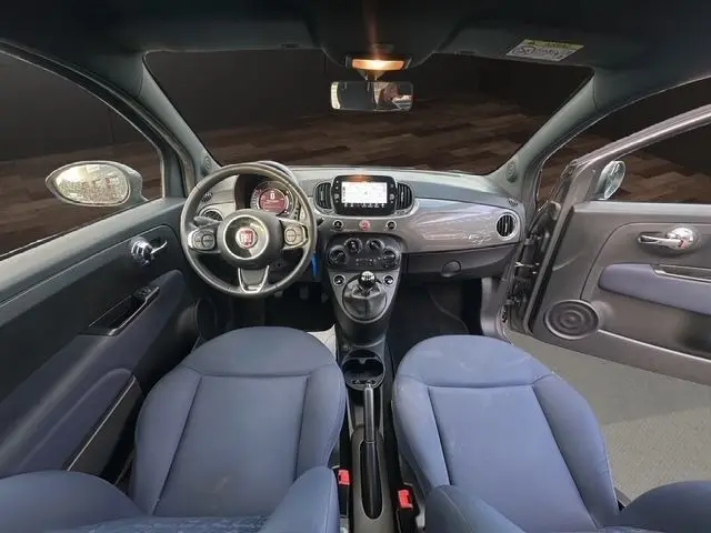 Vue intérieure avant de la Fiat 500 gris foncé 2022, volant cuir multifonctions et écran tactile central visible.