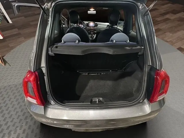 Vue arrière ouverte d'une FIAT 500 gris foncé montrant le coffre vide et l'intérieur avec tableau de bord éclairé.