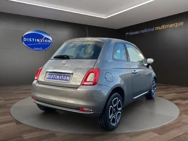 Vue 3/4 arrière droite d'une Fiat 500 gris foncé 2022 en hybride essence, avec jantes distinctives et toit fermé.