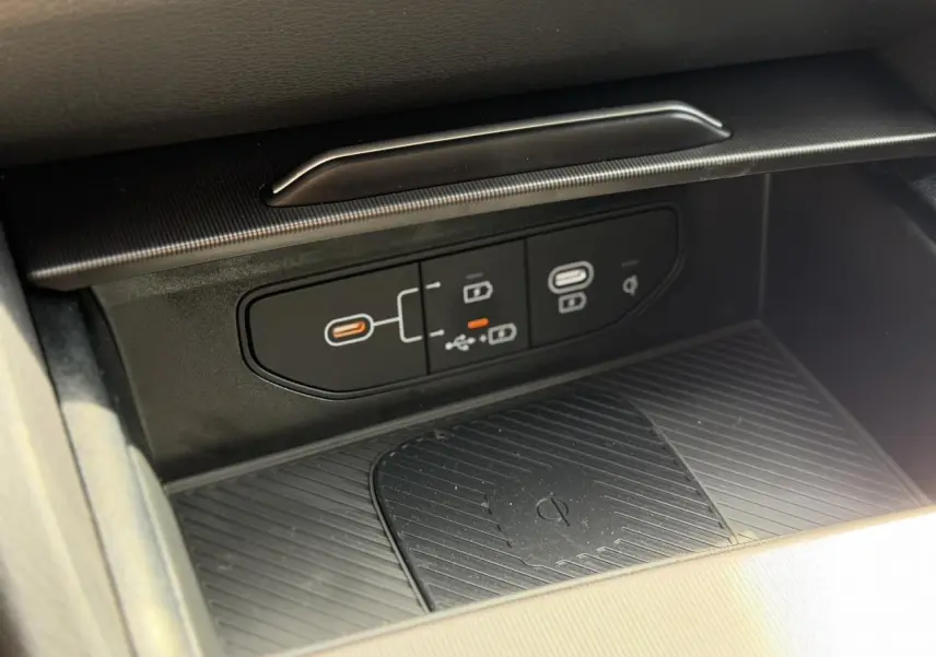 Gros plan sur la console centrale noire avec ports USB-C et zone de recharge sans fil du Kia Sportage blanc 2026.