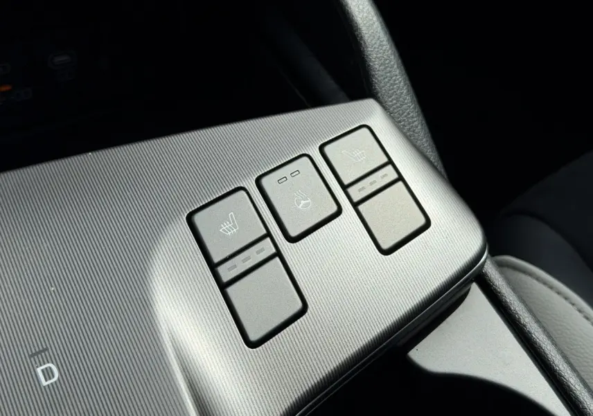 Gros plan sur les boutons de chauffage et ventilation des sièges du KIA SPORTAGE blanc, version GT-line 2026.