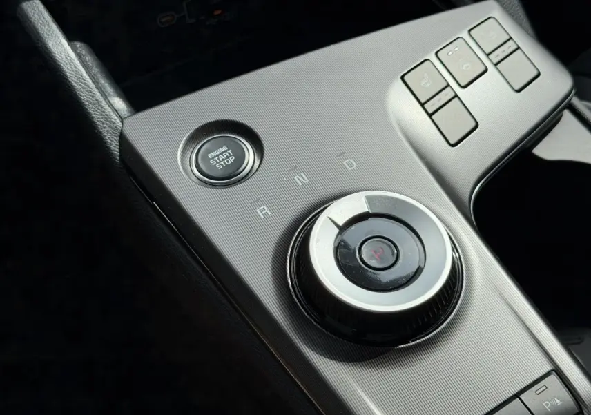 Gros plan sur la console centrale grise du Kia Sportage 2026 avec bouton start/stop et molette de sélection de vitesse.