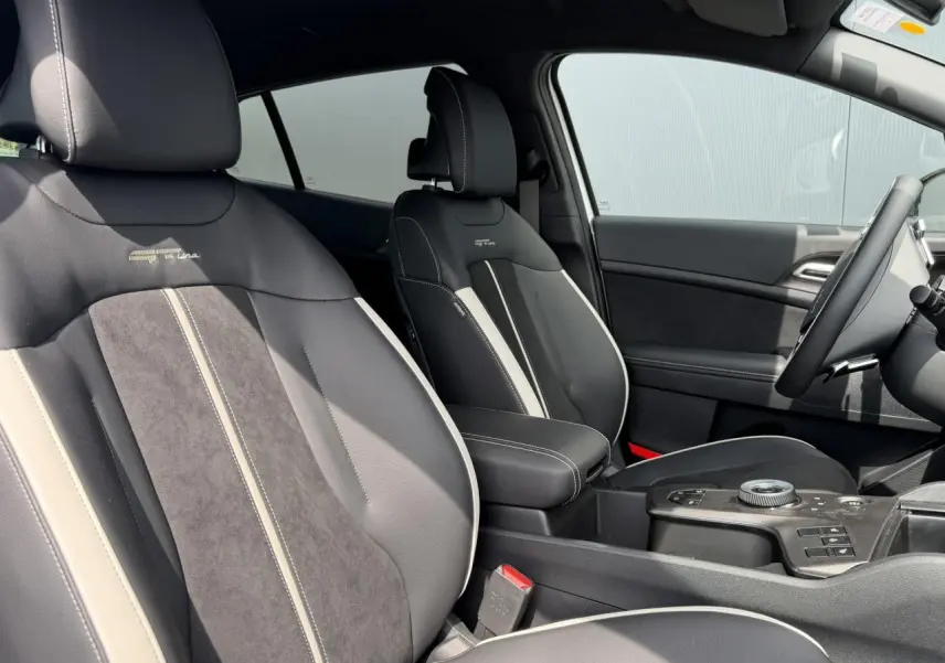 Vue intérieure côté conducteur du Kia Sportage 2026 GT-line, sièges bi-ton noir et gris avec surpiqûres blanches.