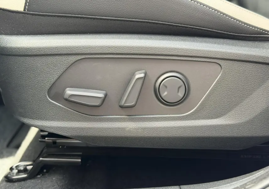 Gros plan sur les commandes électriques de réglage du siège avant côté conducteur du Kia Sportage blanc 2026.