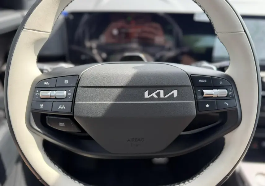 Volant bi-ton noir et beige du Kia Sportage 2026, avec commandes intégrées et logo Kia central visible.