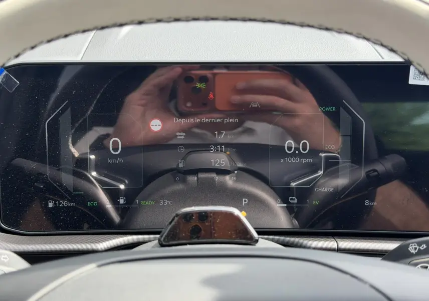 Tableau de bord digital 12,3'' du Kia Sportage blanc, affichage vitesse, autonomie et mode hybride.