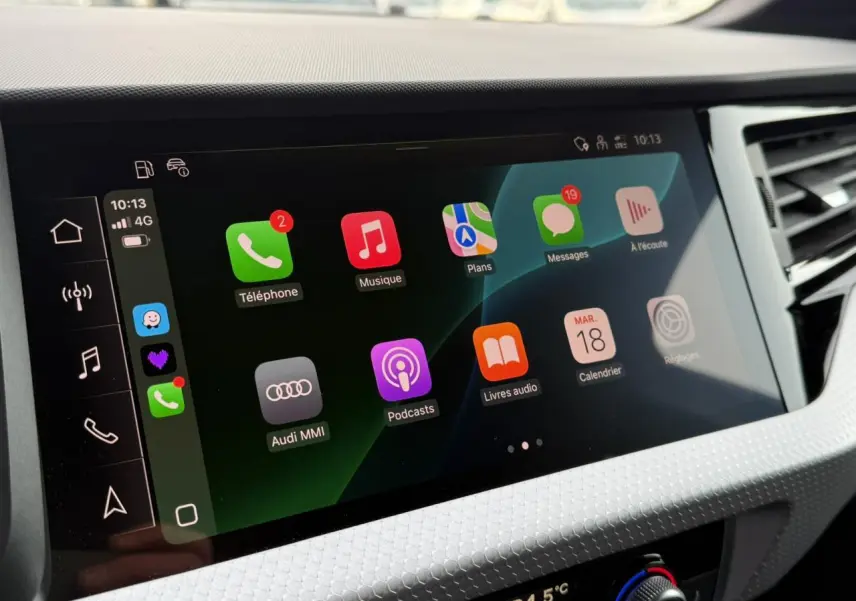 Écran tactile central de l'Audi A1 Sportback 2023 affichant Apple CarPlay avec icônes colorées sur fond noir.