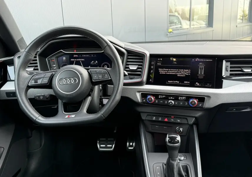 Vue intérieure du poste de conduite de l'Audi A1 Sportback 30 TFSI 110 S-Tronic Competition avec volant sport et écran digital.