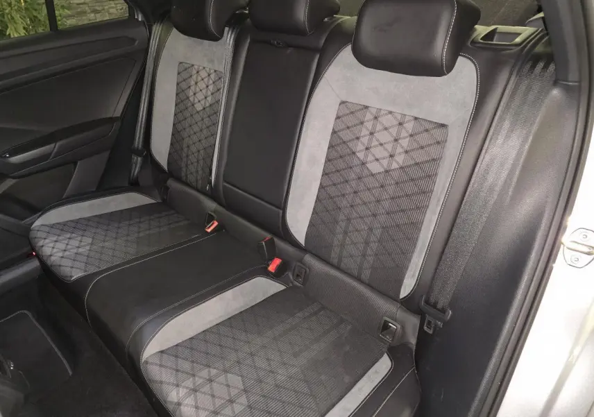 Vue intérieure sur la banquette arrière du Volkswagen T-Roc 2025 avec sellerie tissu et similicuir gris à motifs géométriques.